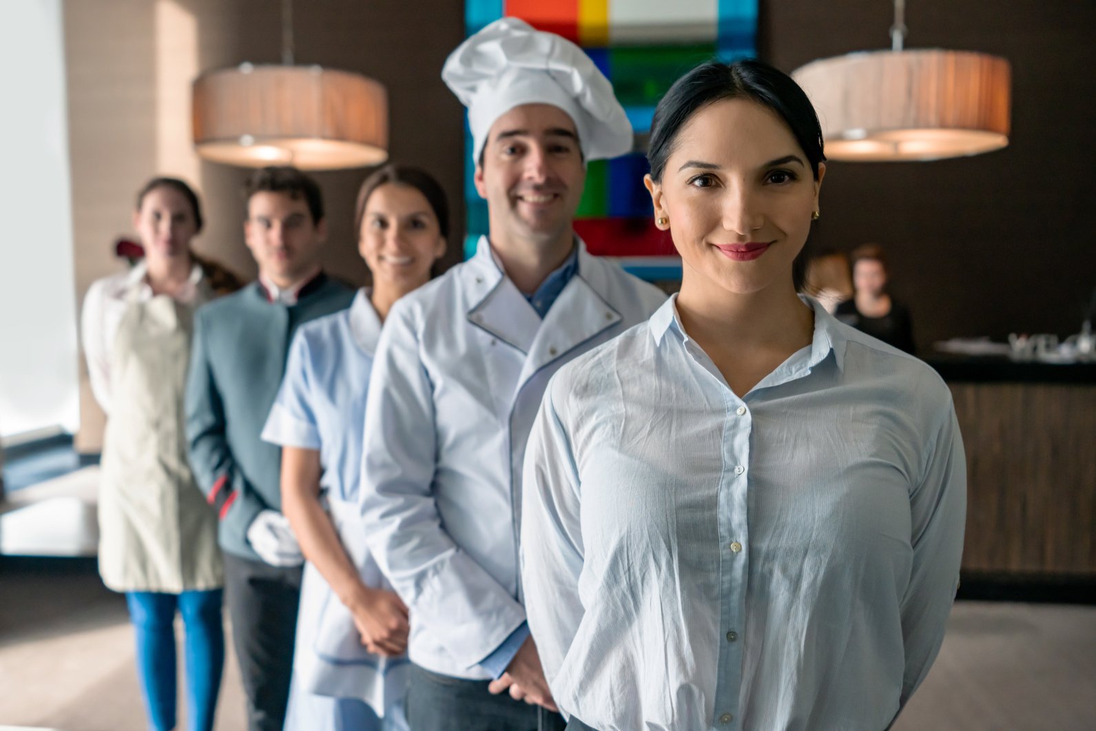 Professional hotel staff at a luxury hotel all facing camera smiling standing behind female manager